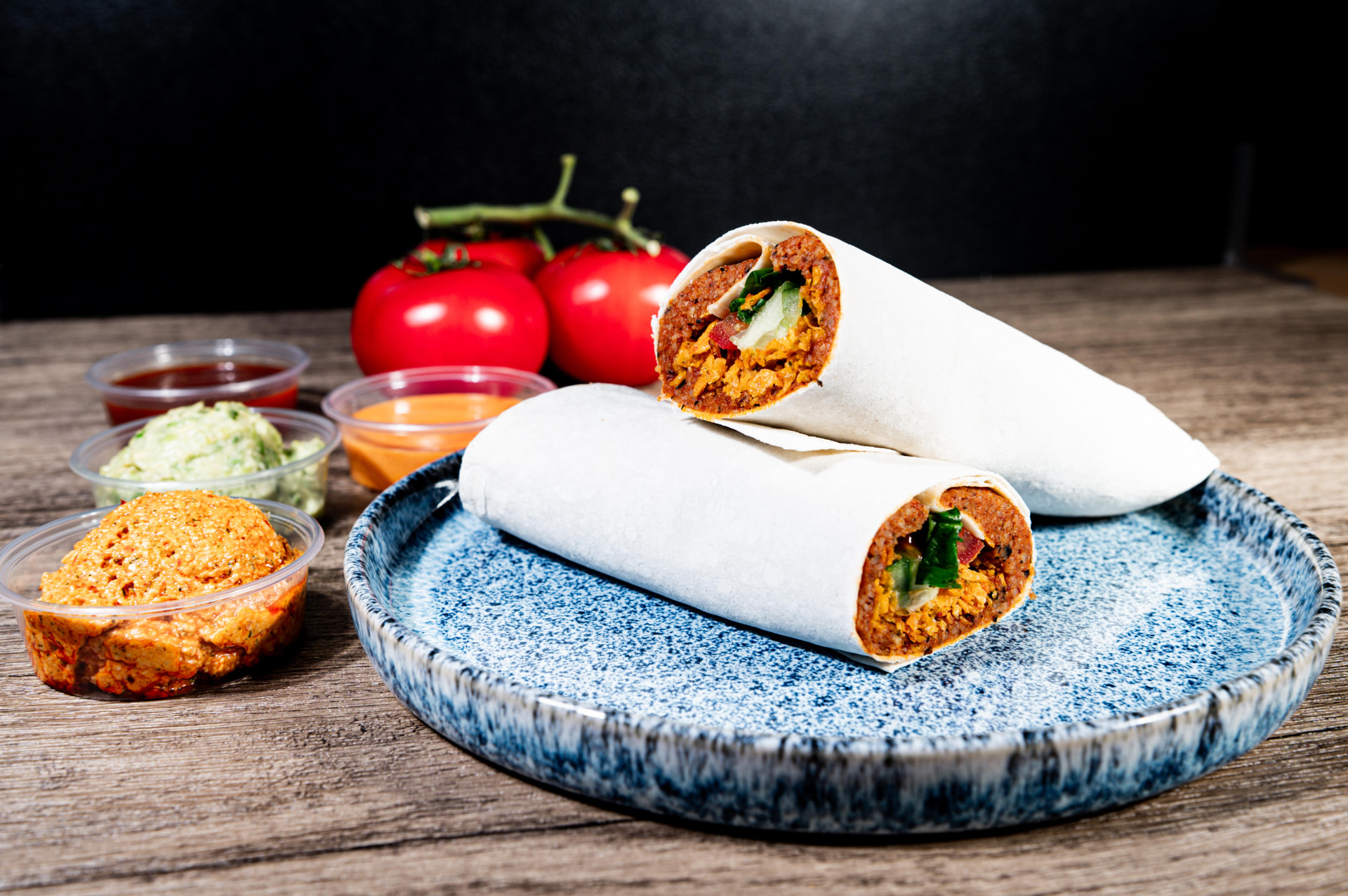 CIBO Çiğköfte Wrap auf blauem Teller mit Saucen und Tomaten